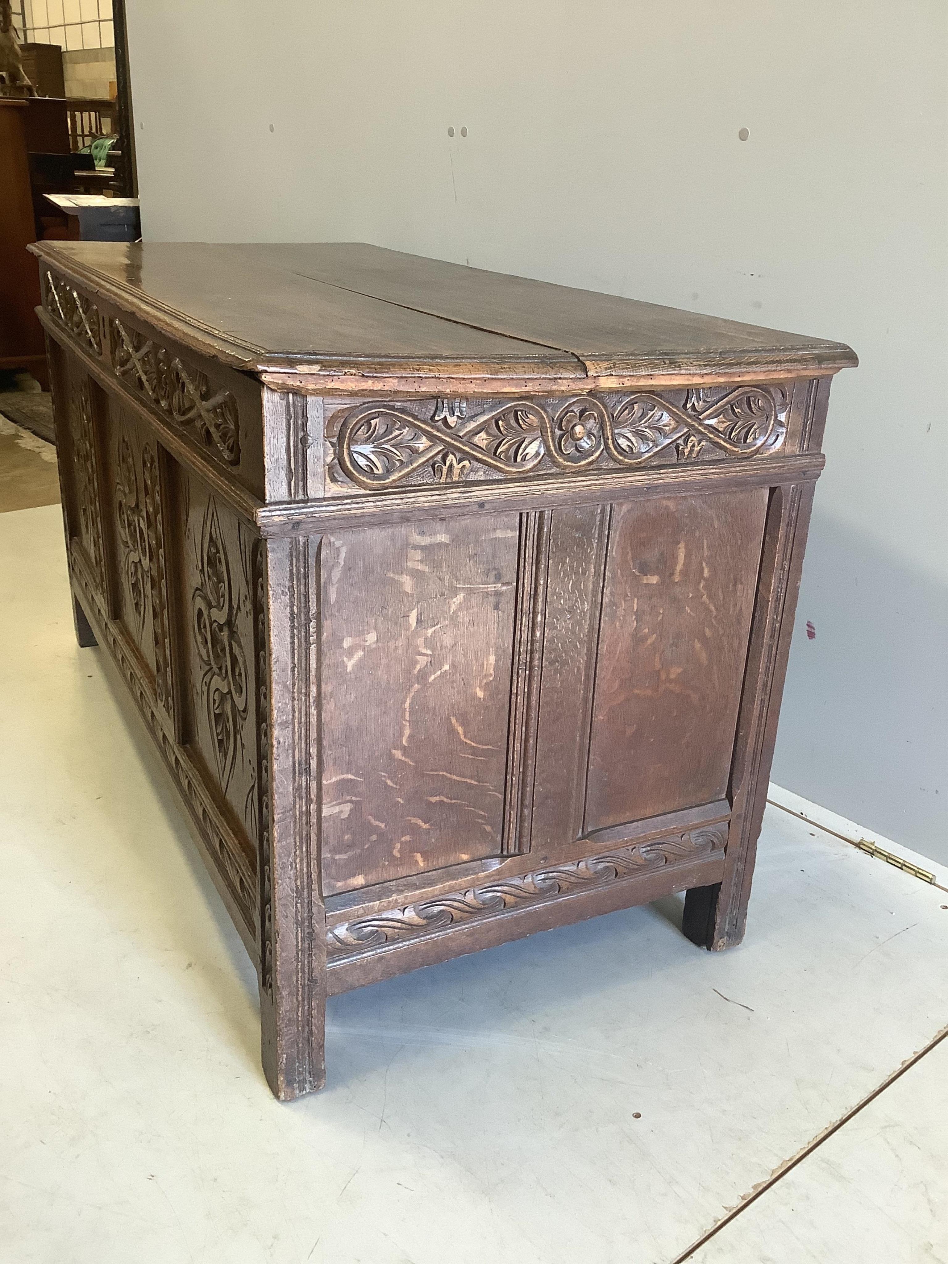 An early 18th century carved oak coffer with two plank top, width 133cm, depth 59cm, height 70cm